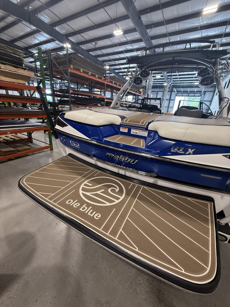 Tan GatorStep swim platform with Ole Blue logo on a blue wakeboat