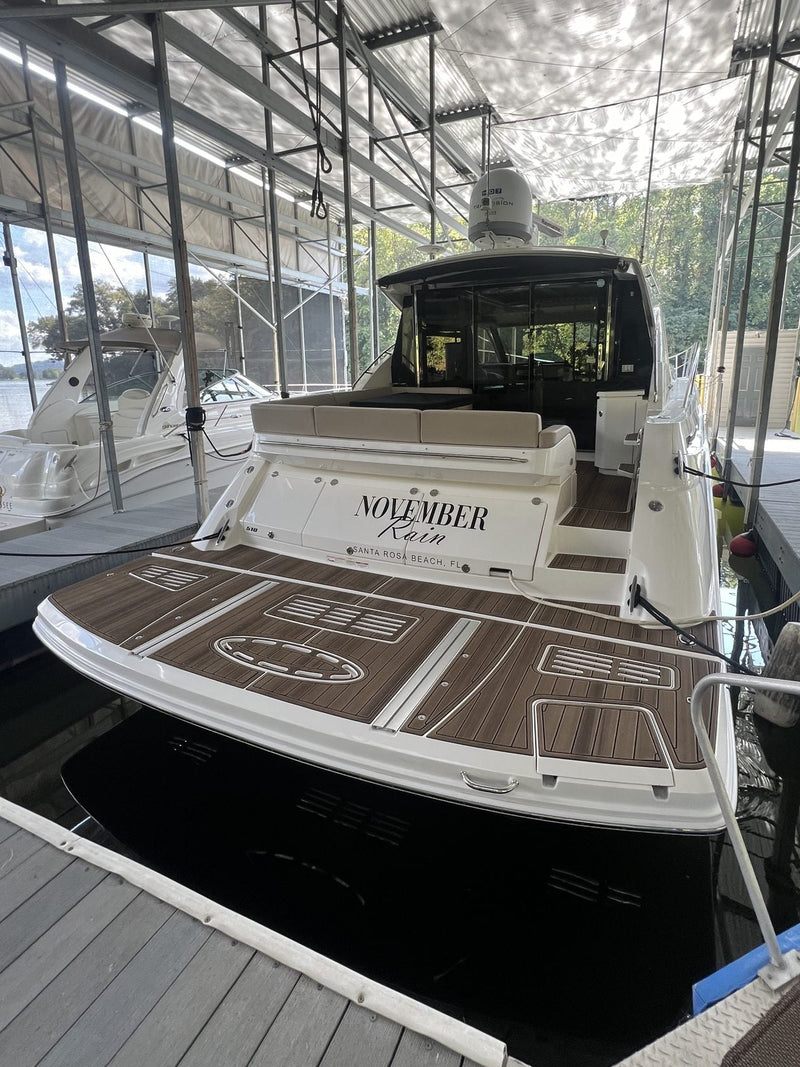 Brown teak GatorStep swim platform with custom name inlay on a cabin cruiser