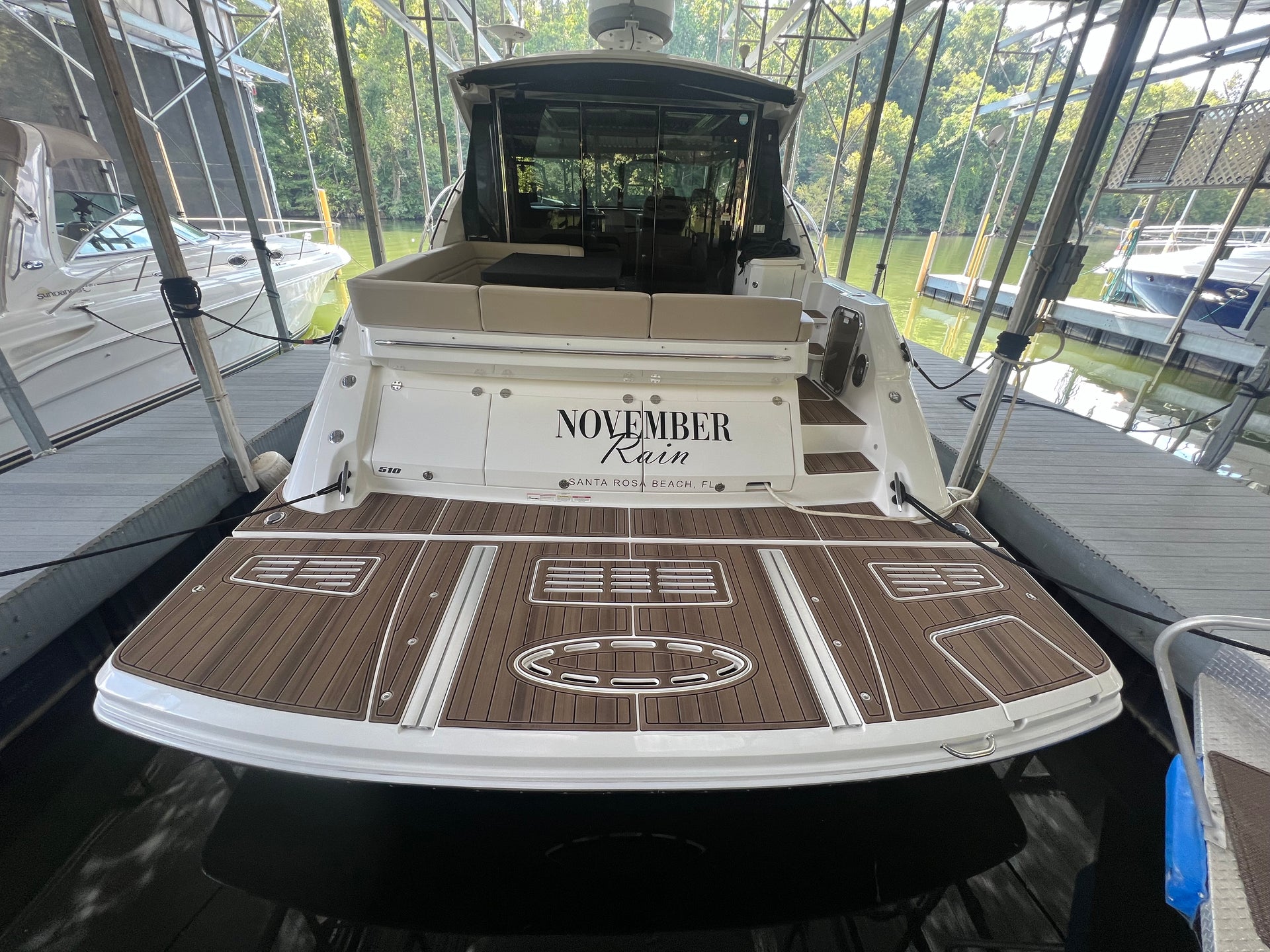 White cabin cruiser on a lift with tan teak-style GatorStep swim platform